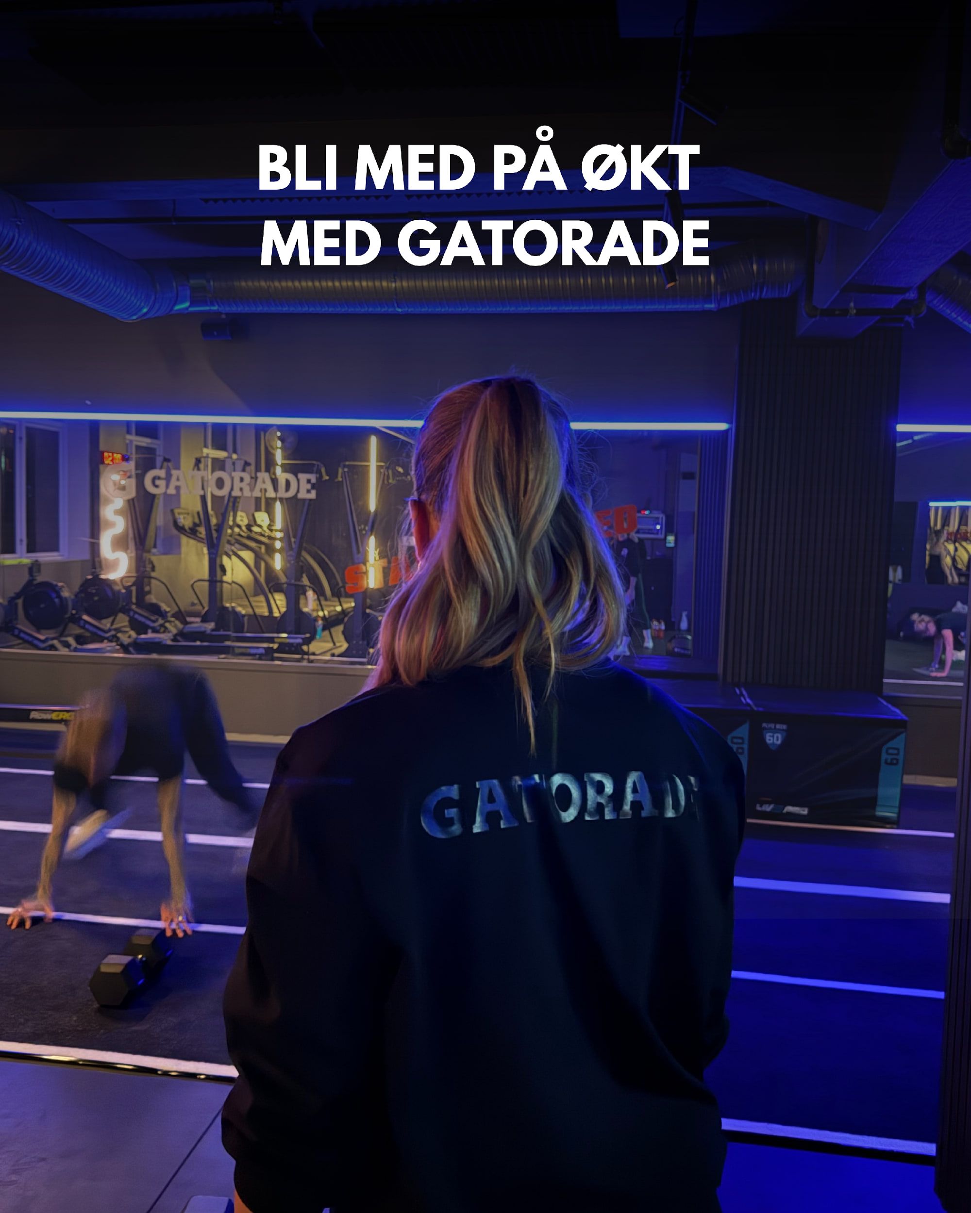 En kvinne i svart Gatorade-jakke, sett bakfra, følger med på en økt i et treningssenter med blått lys. Øverst står «Bli med på økt med Gatorade».